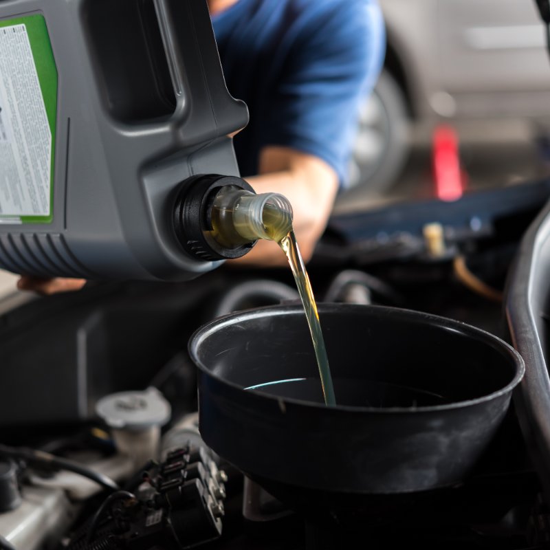 close-up of a mechanic pouring oil into a car engine