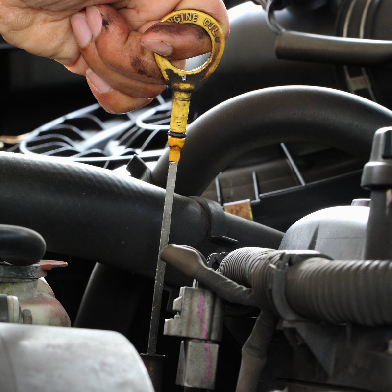 close-up of a mechanic checking the oil level in a car