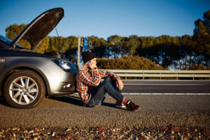 39060018 - young brutal man sits near car talking on cell phone because his auto broken down. thoughtful 20s mixed race caucasian asian male on a beautiful bright sunny summer day trying to call friend that they help repair car.